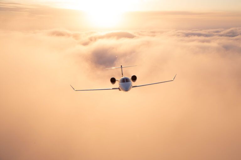 Above yellow sun tinted clouds flies an airplane