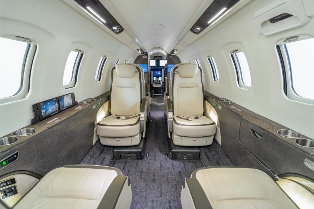 Interior shot of seats paneling and carpet in the middle of a private Learjet