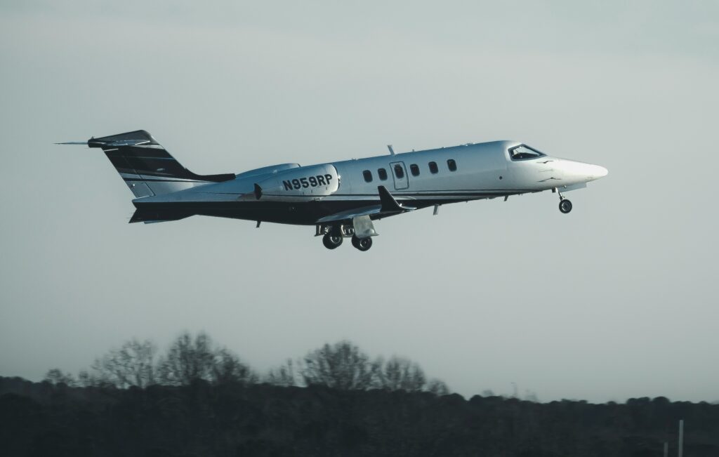 A learjet in white and black takes off in front of grey skies